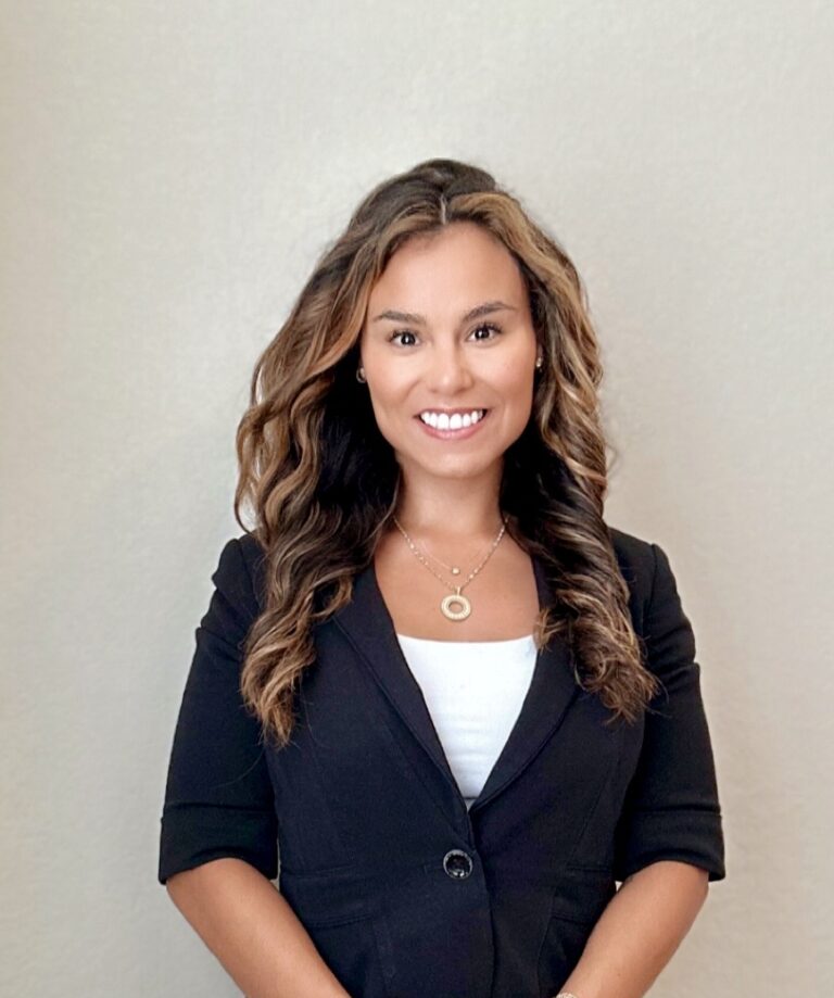 Cristina Blackwood Headshot, standing in black suit against neutral background